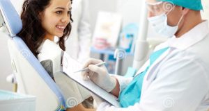 dental assistant chair dental consultation young female patient looking dentist making notes