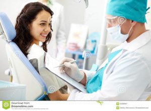 dental assistant chair dental consultation young female patient looking dentist making notes
